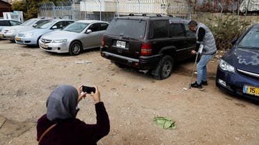 A woman photographs a vandalized vehicle in the Sheikh Jarrah neighborhood of east Jerusalem, Nov. 19, 2021. (AP/Mahmoud Illean)