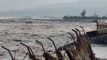 A rescue team delivers rations and essential supplies to Chukum village across the flooded Kosi river, with the broken retaining wall of the Lemon Tree hotel seen on right, in Uttarakhand state, India,  Oct. 20, 2021. (AP)