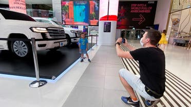 A man takes a picture of a boy standing next to a full-size model of the Land Cruiser 300 made of Lego bricks as it is unveiled by Al-Futtaim Toyota, in Dubai, United Arab Emirates, on November 21, 2021.  (Reuters)