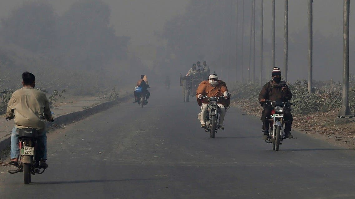 Motorcyclists drive along a road as smog envelops the area of Lahore, Pakistan, Monday, Nov. 22, 2021. (AP)