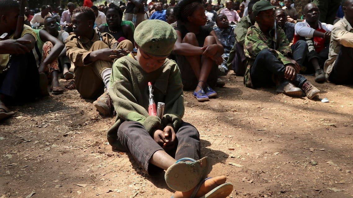 In this Feb. 7, 2018, file photo, a young child soldier sits on the ground at a release ceremony, where he and others laid down their weapons and traded in their uniforms to return to “normal life”, in Yambio, South Sudan. (AP/Sam Mednick)