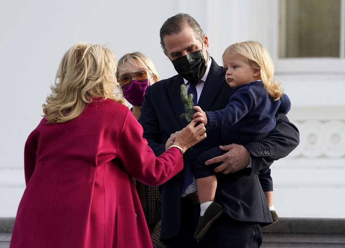 US first lady Jill Biden hands a sprig from the tree to Beau Biden as parents Hunter Biden and Melissa Cohen watch during an event to receive the White House Christmas tree in Washington, D.C., US, on November 22, 2021. (Reuters)