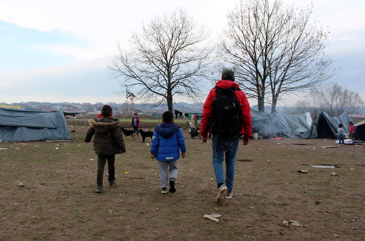 Ibrahim Rasool, Afghan refugee, formerly a FIFA-licensed futsal referee (right), walks with children at a makeshift camp housing migrants, in Velika Kladusa, Bosnia, on Nov. 13, 2021. (AP)