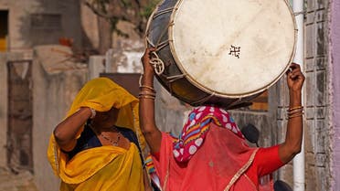 A woman carries a drum on her head as she walks through a street to perform at a wedding ceremony on the outskirts of Ajmer, India, April 22, 2021. (AFP)