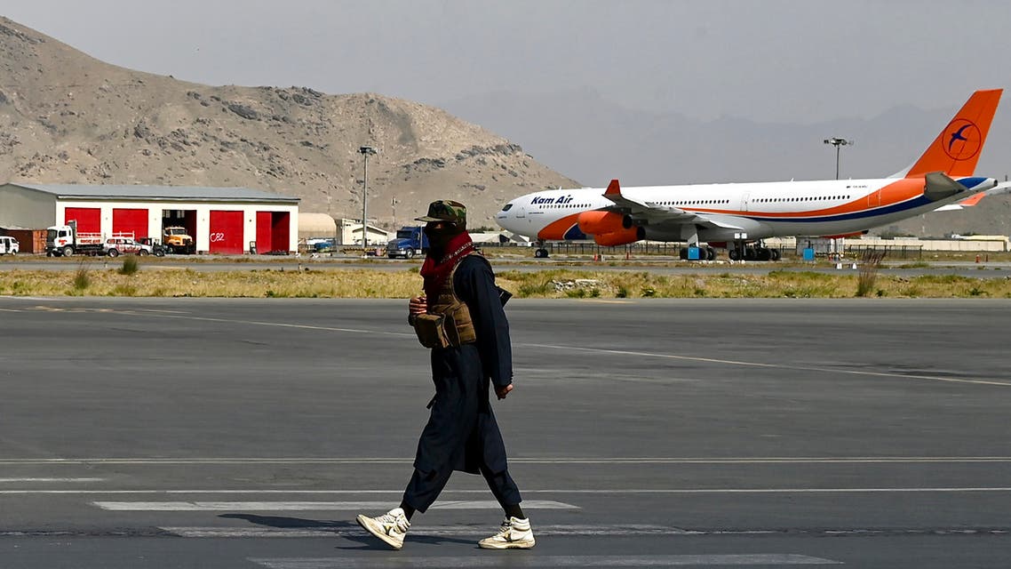 A Taliban fighter walks at the airport in Kabul on October 26, 2021. (Photo by Wakil Kohsar / AFP)