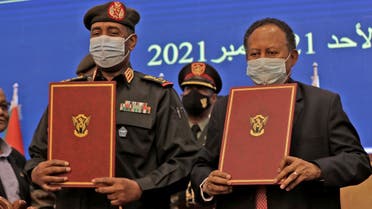 Sudan's top general Abdel Fattah al-Burhan (L) and Prime Minister Abdalla Hamdok lift documents during a deal-signing ceremony to restore the transition to civilian rule in the country in the capital Khartoum, on November 21, 2021. (AFP)