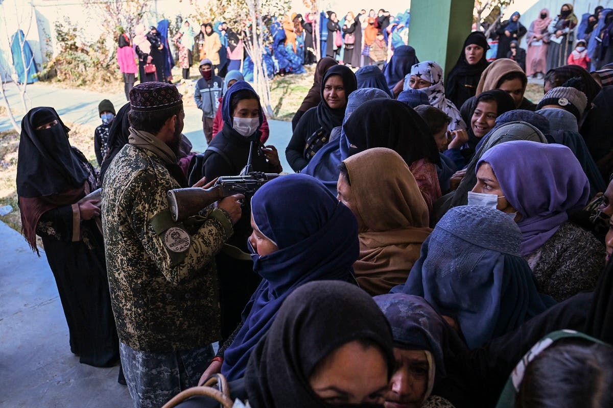 A Taliban fighter tries to keep order as women wait in a queue during a World Food Program cash distribution in Kabul on November 29, 2021. (Hector Retamal/AFP)