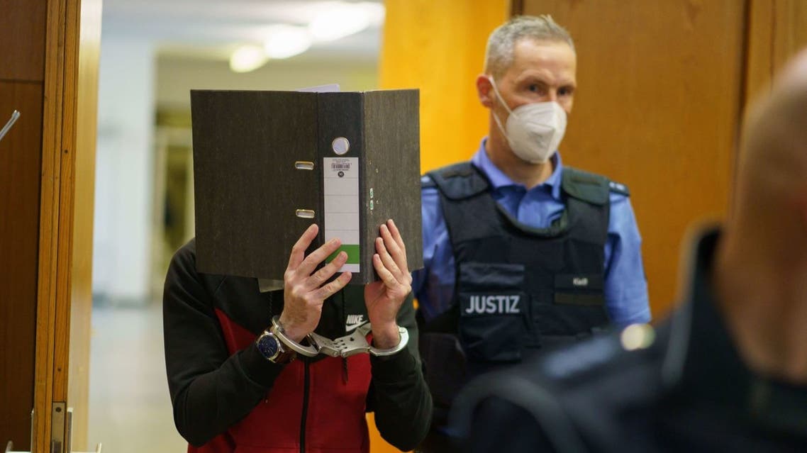 The defendant Iraqi Taha Al-Jumailly (L) is led into the courtroom for the sentencing in his trial for charges of genocide, crimes against humanity, war crimes, human trafficking and murder at the Higher Regional Court (OLG) in Frankfurt am Main, western Germany, on November 30, 2021. (AFP)
