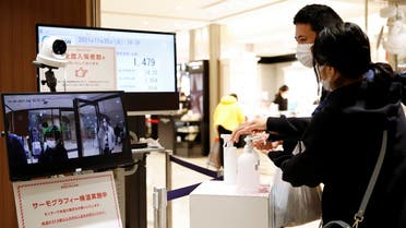 People disinfect their hands while a thermal camera reads their temperature, at the entrance of a department store, on the first day of Japan's closed borders to prevent the spread of the Omicron variant of coronavirus, in Tokyo, Japan, on November 30, 2021. (Reuters)