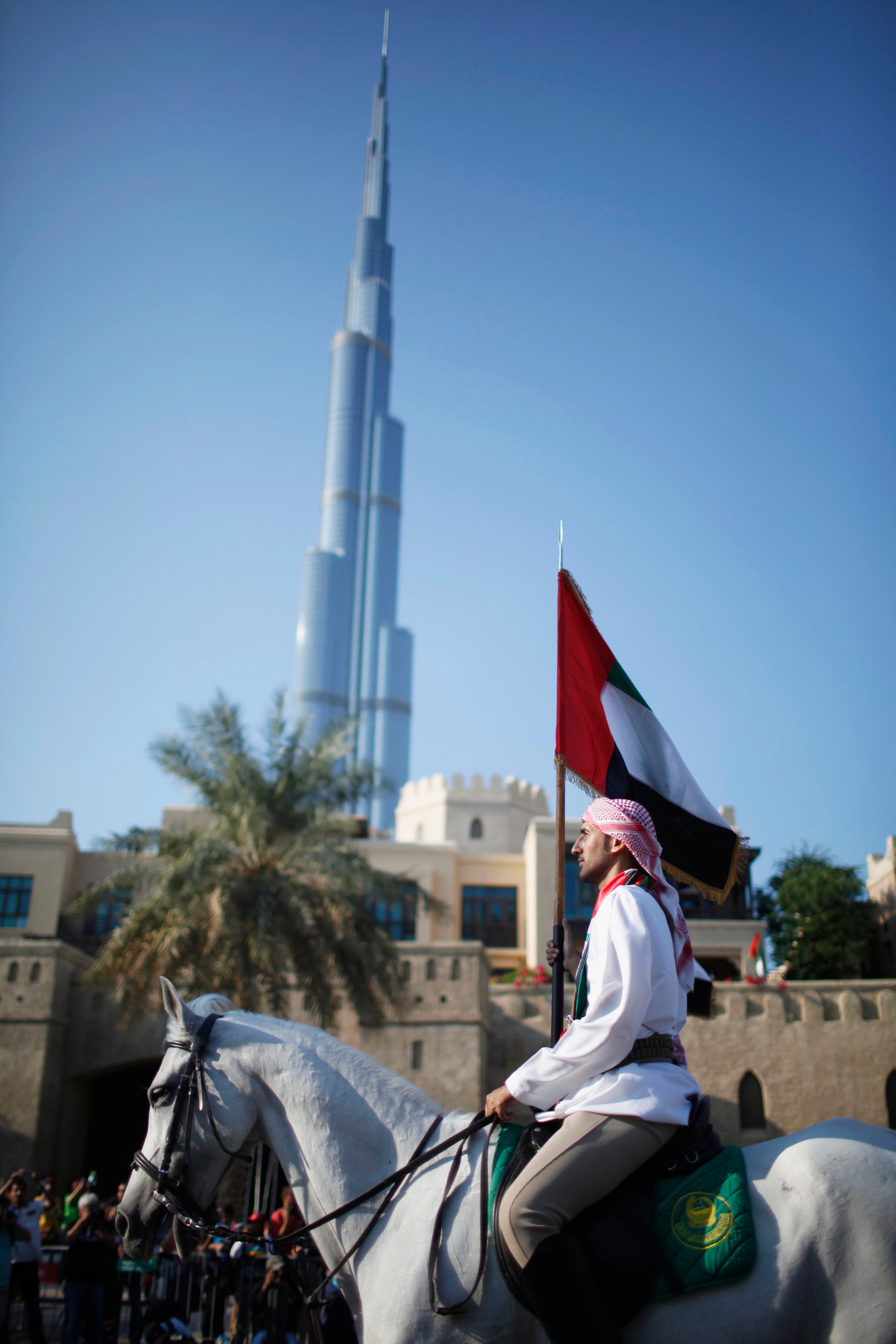 A man holds a national flag as he rides a horse in front of Burj Khalifa during parade celebrating 41st National Day of the United Arab Emirates, in downtown Dubai. (Reuters)