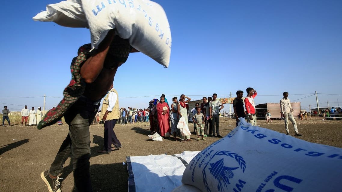 Ethiopian refugees who fled fighting in the Tigray Region watch workers unload World Food Programme food aid at the Village 8 border reception center in Sudan's eastern Gedaref State, on November 20, 2020. (AFP)