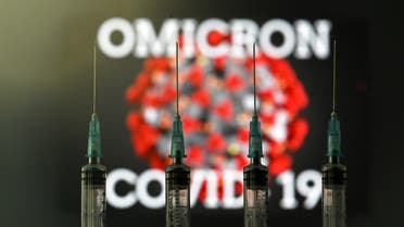 An illustration picture taken in London on December 2, 2021 shows four syringes and a screen displaying the word 'Omicron', the name of the new covid 19 variant, and an illustration of the virus. (Photo by Justin TALLIS / AFP)