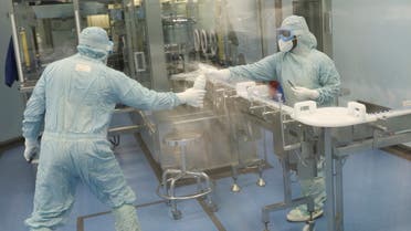 Workers at the South African pharmaceutical major Aspen Pharmacare pass a bottle at its Johnson & Johnson COVID-19 vaccine facility in Gqeberha, South Africa, October 25, 2021. Picture taken through glass. REUTERS/Siphiwe Sibeko
