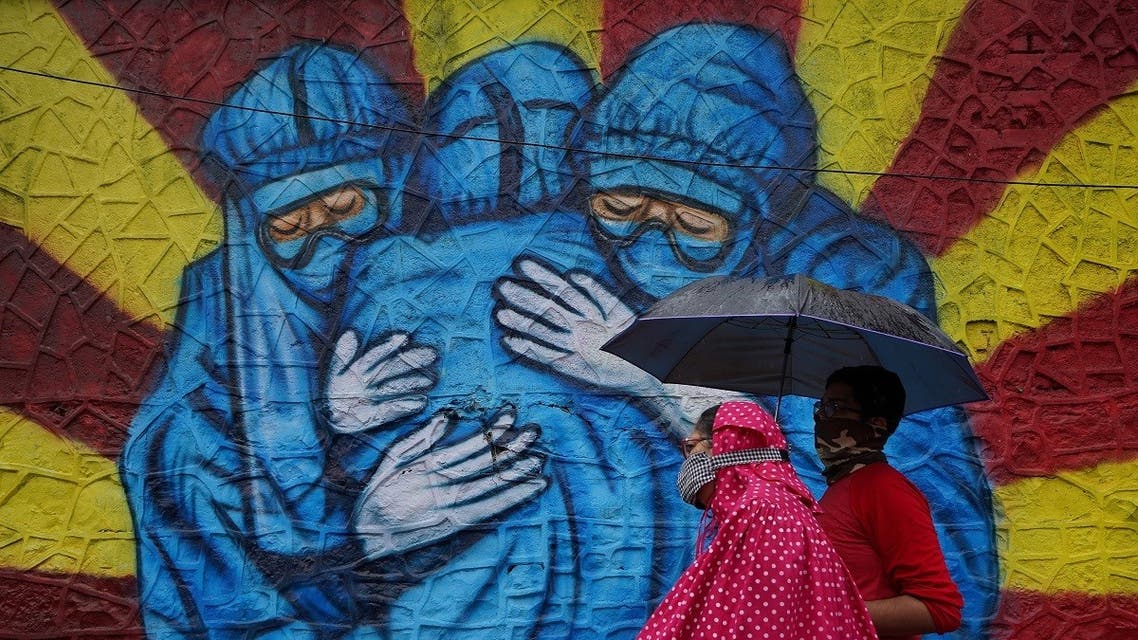 A woman and her son walk past a graffiti on a street, amidst the coronavirus disease (COVID-19) pandemic, in Mumbai, India, December 1, 2021. (Reuters)
