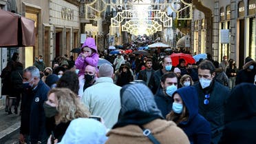 People wear protective face masks as they walk along the Via Condotti luxury shopping street in central Rome on December 05, 2021. (Vincenzo Pinto/AFP)