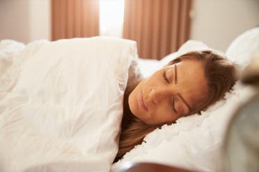 A woman sleeps in a bed. (Stock photo)