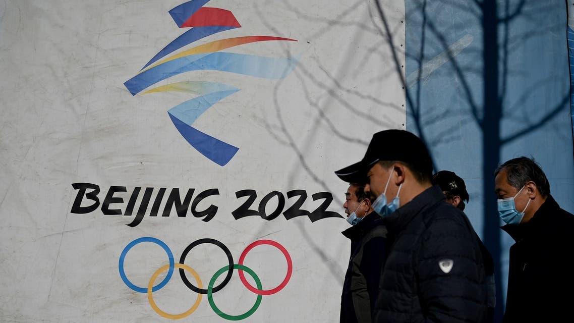 People walk past the Beijing 2022 Winter Olympics logo at the Shougang Park in Beijing on December 1, 2021. (Photo by Noel Celis / AFP)