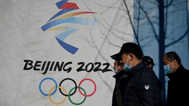 People walk past the Beijing 2022 Winter Olympics logo at the Shougang Park in Beijing on December 1, 2021. (Photo by Noel Celis / AFP)