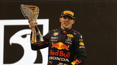 Red Bull's Max Verstappen celebrates winning the race and the world championship on the podium with the trophy. (Reuters)