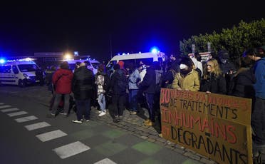 Members of associations for the defense of migrants gather next to a placard reading “30 years of announcements, of inhuman and degrading treatment” on November 24, 2021 in Calais, northern France, following the sinking of a migrant boat crossing the Channel to England. (AFP)