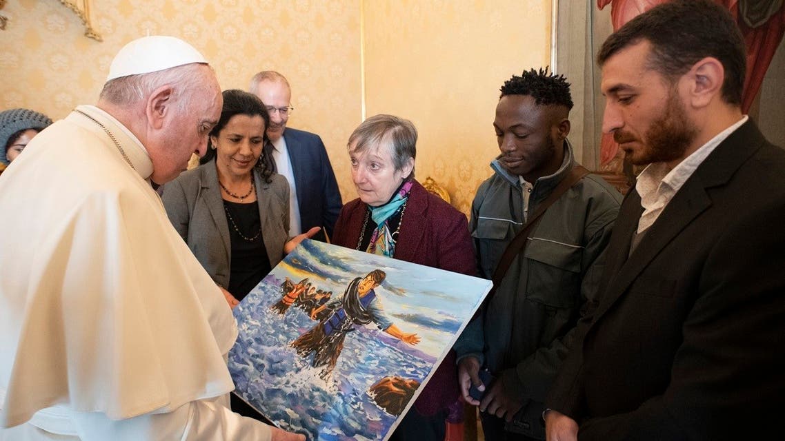 Pope Francis look at a painting during a meeting in The Vatican with refugees hosted by the Community of Sant’Egidio, December 17, 2021. (Handout/Vatican Media/AFP)