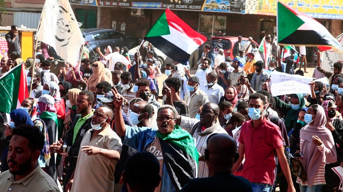 Sudanese demonstrators raise national flags and banners as they rally against the military chief who launched an October 25 coup followed by a bloody crackdown, in the northern part of the capital Khartoum, on December 19, 2021. (AFP)