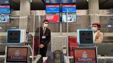 Emirates airlines employees behind check in counters equipped with a fast-track identification system that uses face and iris-recognition technologies, at Dubai international airport, on March 7, 2021. (AFP)