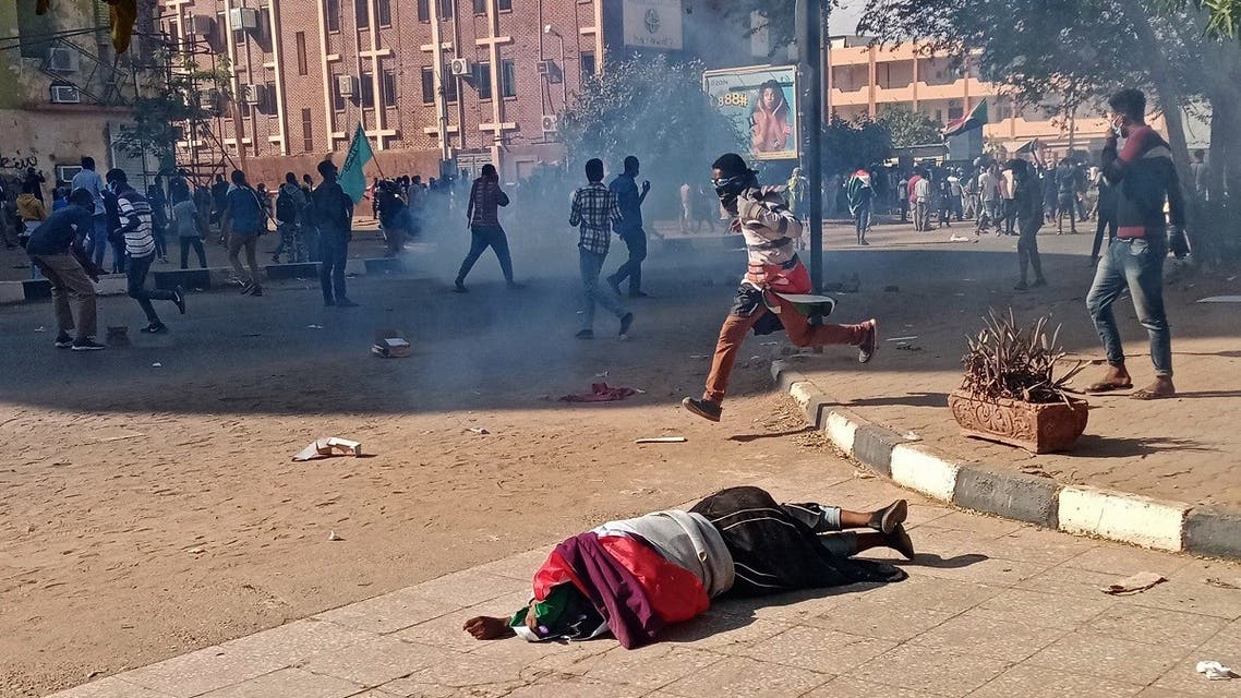 A wounded Sudanese protester falls on the pavement after security forces fired tear gas during a rally to mark three years since the start of mass demonstrations that led to the ouster of strongman Omar al-Bashir, in the capital Khartoum on December 19, 2021.  (AFP)