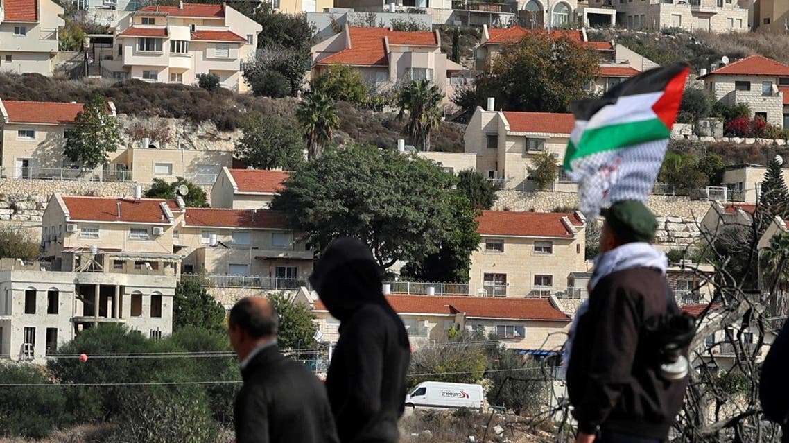 Palestinian protesters wave a national flag during a demonstration in the village of Kfar Qaddum, near the Jewish settlement of Kedumim in the occupied West Bank, against the expropriation of land by Israel on December 3, 2021. (AFP)