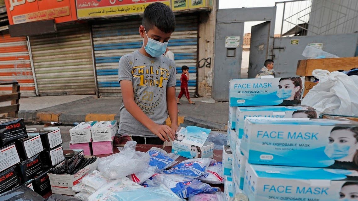 An Iraqi boy sells medical masks at a popular market in central Baghdad on July 26, 2021. (AFP)
