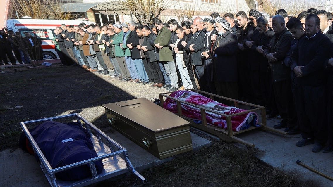 People pray next to bodies of Iraqi Kurdish migrants, who drowned while trying to cross the channel between France and Britain, in the town of Rania, Sulaimaniyah province, Iraq, on December 26, 2021. (Reuters)