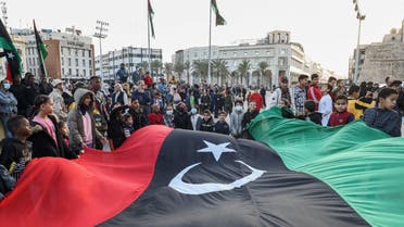 Children wave a giant Libyan national flag as people gather at the Martyrs' Square in the centre of Libya's capital Tripoli on December 24, 2021, to mark the country's 70th independence day. (AFP)