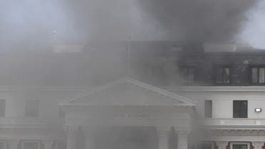 Smoke billows from the roof of a building at the South African Parliament precinct in Cape Town on January 2, 2022, during a fire incident. (AFP)