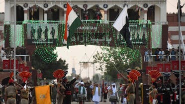 Indian Border Security Force (BSF) (front) personnel and Pakistani Rangers (in black) personnel lower their respective flags during the daily beating retreat ceremony on the eve of the 75th Pakistan Independence day on August 14, at the India-Pakistan Wagah Post some 35 km from Amritsar on August 13, 2021. (AFP)
