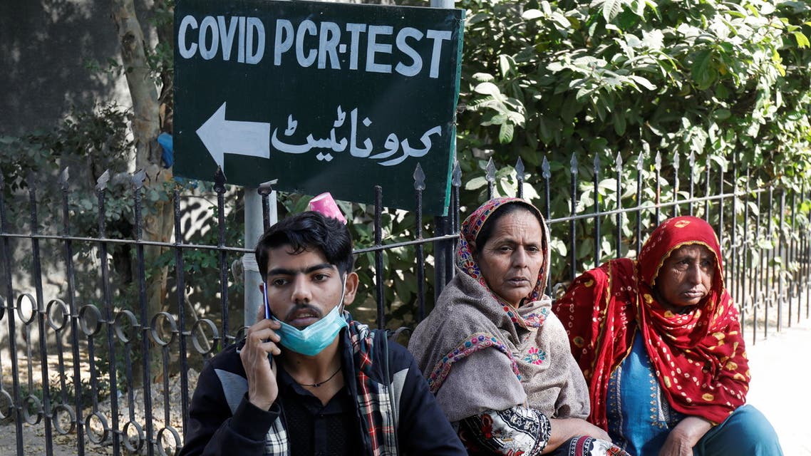 People sit next to a coronavirus disease (COVID-19) test sign outside the School of Nursing in Jinnah Postgraduate Medical Centre (JPMC), in Karachi, Pakistan December 9, 2021. REUTERS/Akhtar Soomro