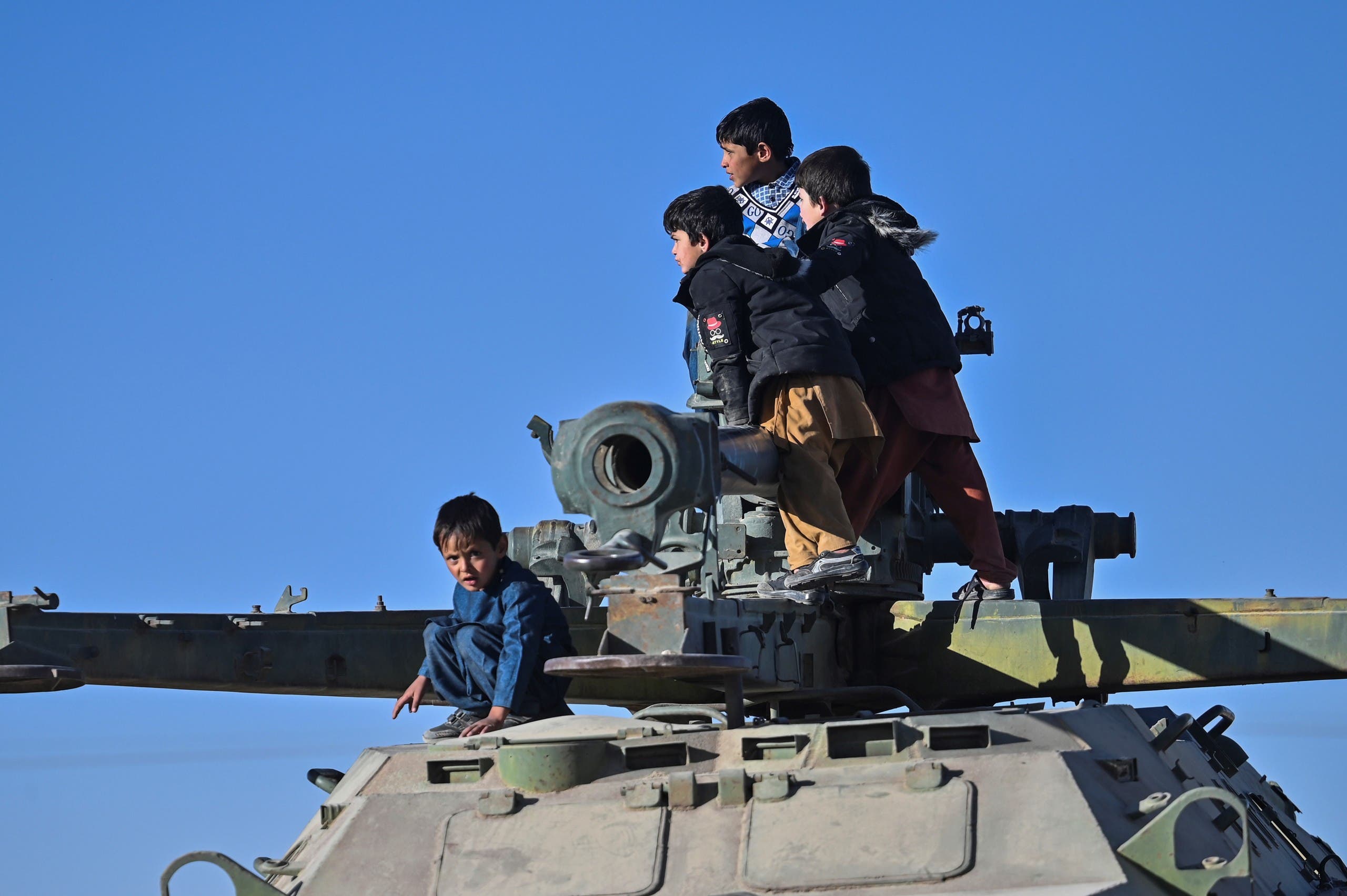 In this picture taken on November 13, 2021, boys play on a destroyed armoured vehicle displayed along a road in Ghazni. On roads outside the city of nearly 200,000, an informal exhibition to the Taliban victory has been erected. (AFP)