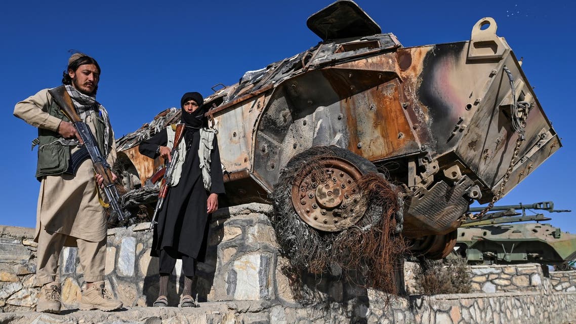 In this picture taken on November 13, 2021, Taliban fighters stand next to destroyed armoured vehicles displayed along a road in Ghazni. On roads outside the city of nearly 200,000, an informal exhibition to the Taliban victory has been erected. Rusting hulks of destroyed American armoured vehicles are on display, their weapons removed, their tyres flat and frayed. (Photo by Hector RETAMAL / AFP) / TO GO WITH 'AFGHANISTAN-US-TALIBAN-HISTORY' BY ELISE BLANCHARD - To go with 'Afghanistan-US-taliban-history' by Elise Blanchard