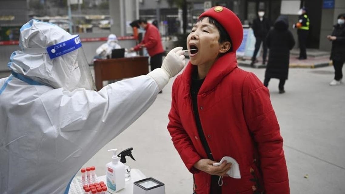 A worker wearing protective gear gives a COVID-19 test to a woman at a testing site in Xi'an in northwestern China's Shaanxi Province, on Jan. 4, 2022. (AP)