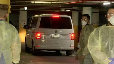 A van, presumedly holding tennis player Novak Djokovic, is surrounded by workers in personal protective equipment in a hotel carpark in Melbourne, Australia, on January 6, 2022 in this still image taken from video. (Reuters)