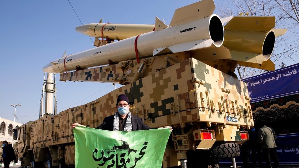 An Iranian man holds a slogan next to missiles displayed at Mosallah mosque on the occasion of second anniversary of an Iran missile attack at a US military base in Iraq following the assassination of a former top Iranian commander, in Tehran, on January 7, 2022. (AFP)