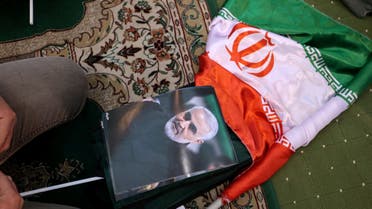 An Iranian man kneels next to a portrait of slain top Iranian commander Qasem Soleimani during a ceremony in the capital Tehran, on January 3, 2022. (AFP)