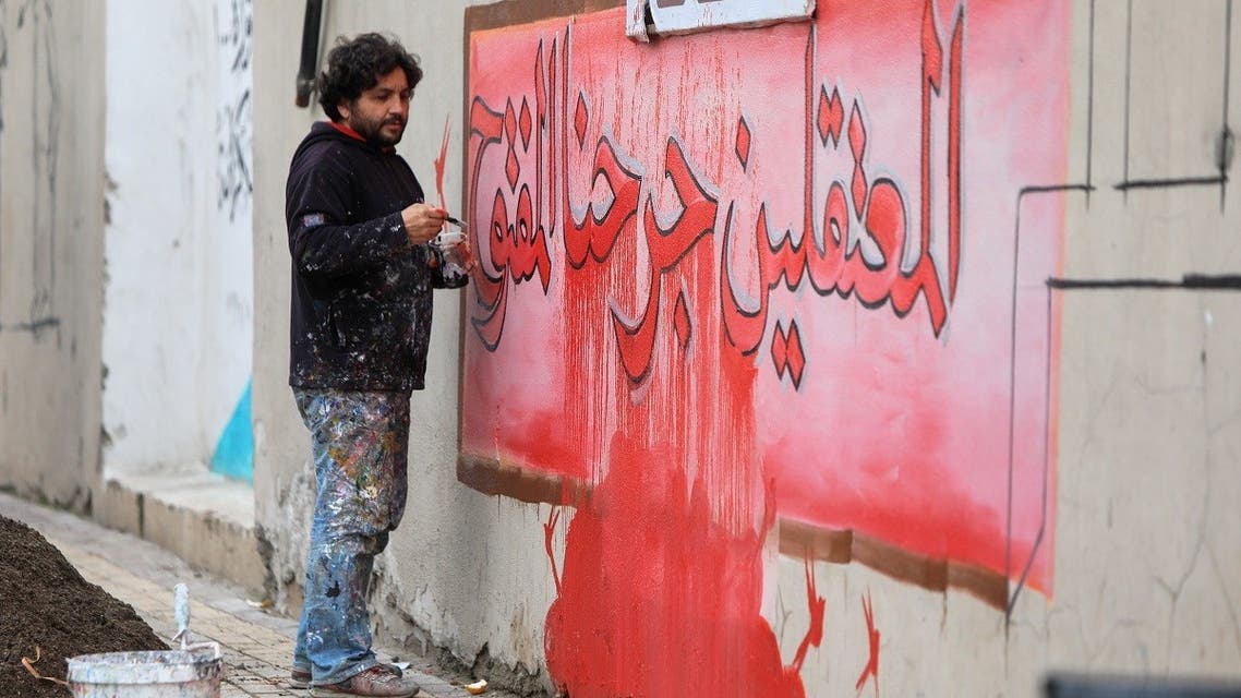 Syrian artist Aziz Asmar draws a mural with the inscription The detainees are our open wound in Aleppo, Jan. 7, 2022. (AFP)