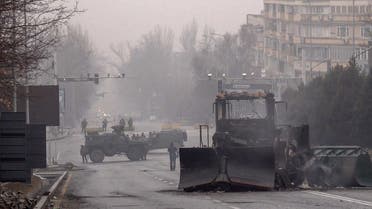 Servicemen and their military vehicles block a street in central Almaty on January 7, 2022, after violence that erupted following protests over hikes in fuel prices. (AFP)