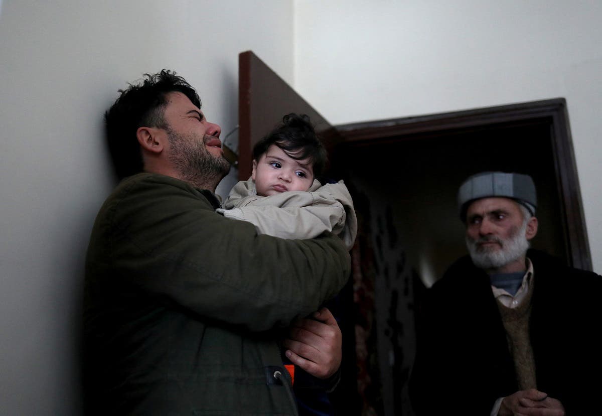 Hamid Safi, a 29-year-old taxi driver who had found baby Sohail Ahmadi in the airport, cries as he holds Sohail before handing him over to his grandfather Mohammad Qasem Razawi in Kabul, Afghanistan, January 8, 2022. (Reuters)