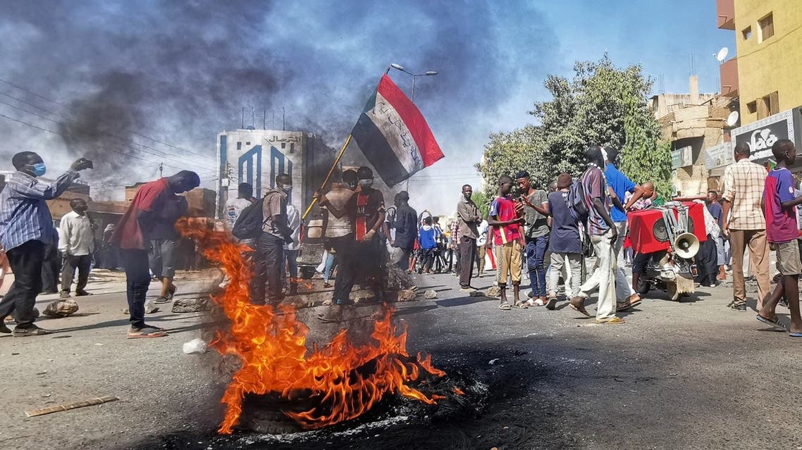 Sudanese protesters walk past burning tyres as they rally to protest against the October 2021 military coup, in the capital Khartoum, on January 9, 2022. (AFP)