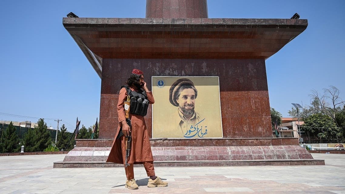 A Taliban fighter stand next to poster bearing the image late Afghan commander Ahmad Shah Massoud in Kabul, Aug. 16, 2021. (AFP)