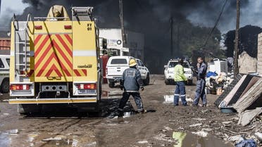 A file photo shows emergency personnel of the South African Police Services (SAPS) stand as smoke billows from the site of a petrol tanker which caught fire in Clairwood Industrial Park in Durban, October 31, 2021. (AFP)