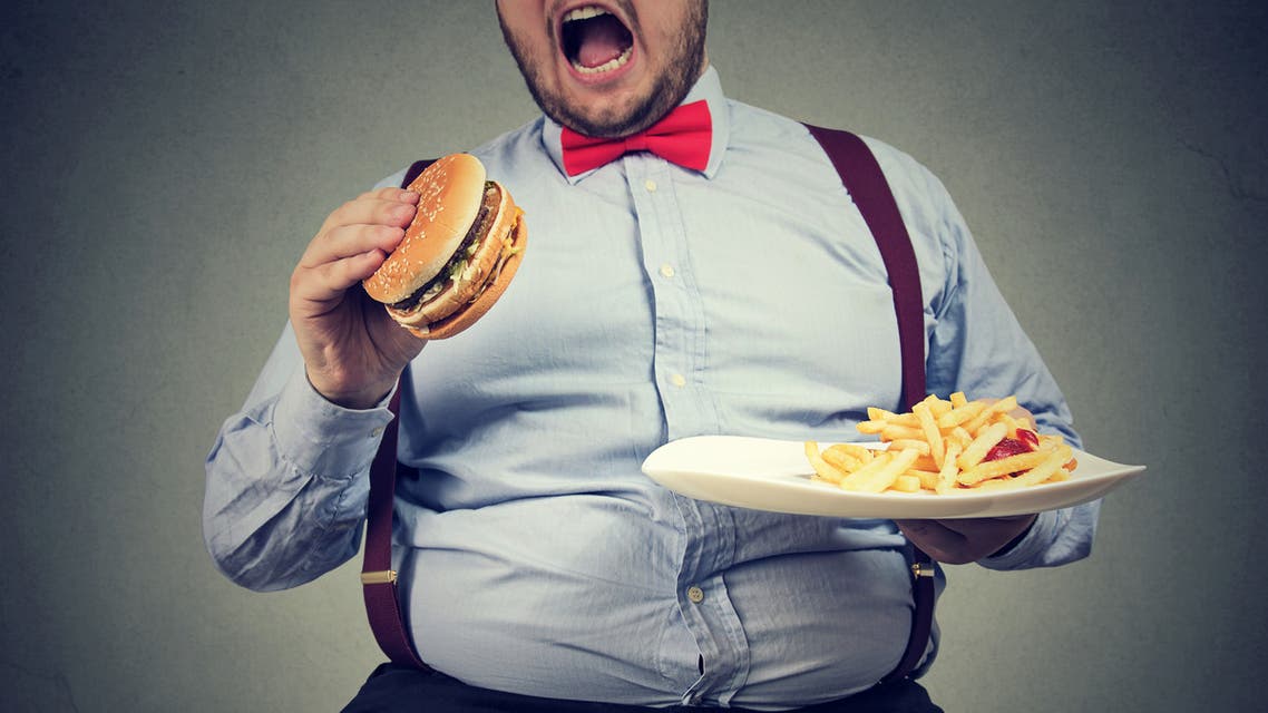 Big man in formal clothes sitting and consuming plate with fast food stock photo