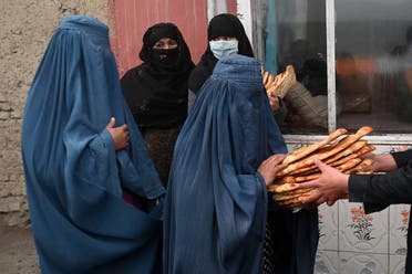 Women wearing a burqa receive free bread distributed as part of the Save Afghans From Hunger campaign in front of a bakery in Kabul on January 18, 2022. (AFP)