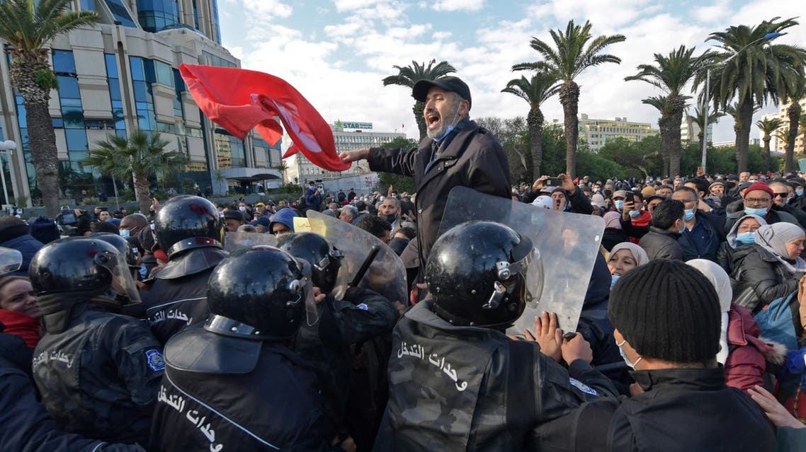 A Tunisian man waves his country's national flag during protests against President Kais Saied, on the 11th anniversary of the Tunisian revolution in the capital Tunis on January 14, 2022. (AFP)
